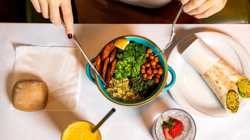 person holding silver spoon and blue ceramic bowl with food